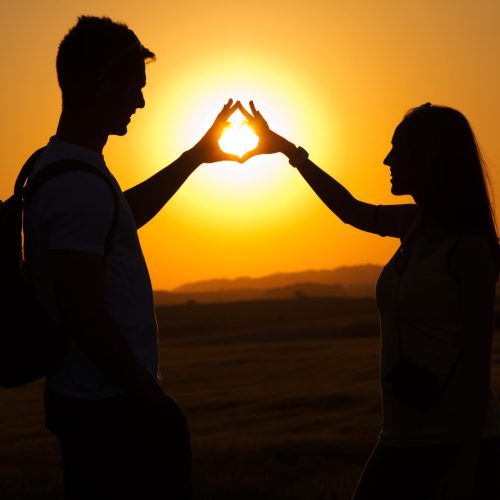 Silhouette portrait of young couple in field.